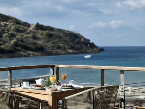 Une table à manger avec des aliments pour le petit-déjeuner et une vue sur la mer.