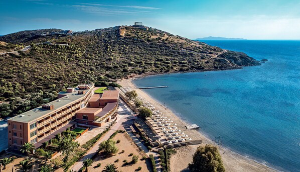 An aerial view of a coastal hotel with a beach, a mountain, and a clear sky. - Aegeon Beach Hotel (Lavreotiki)