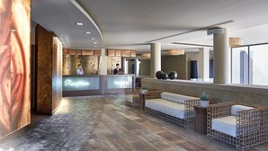 A reception area with a reception desk, seating area, and a large window providing a view. - Aegeon Beach Hotel (Lavreotiki)