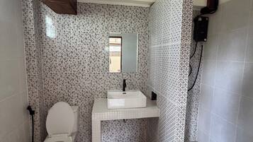 A bathroom with a toilet, sink, and patterned walls.