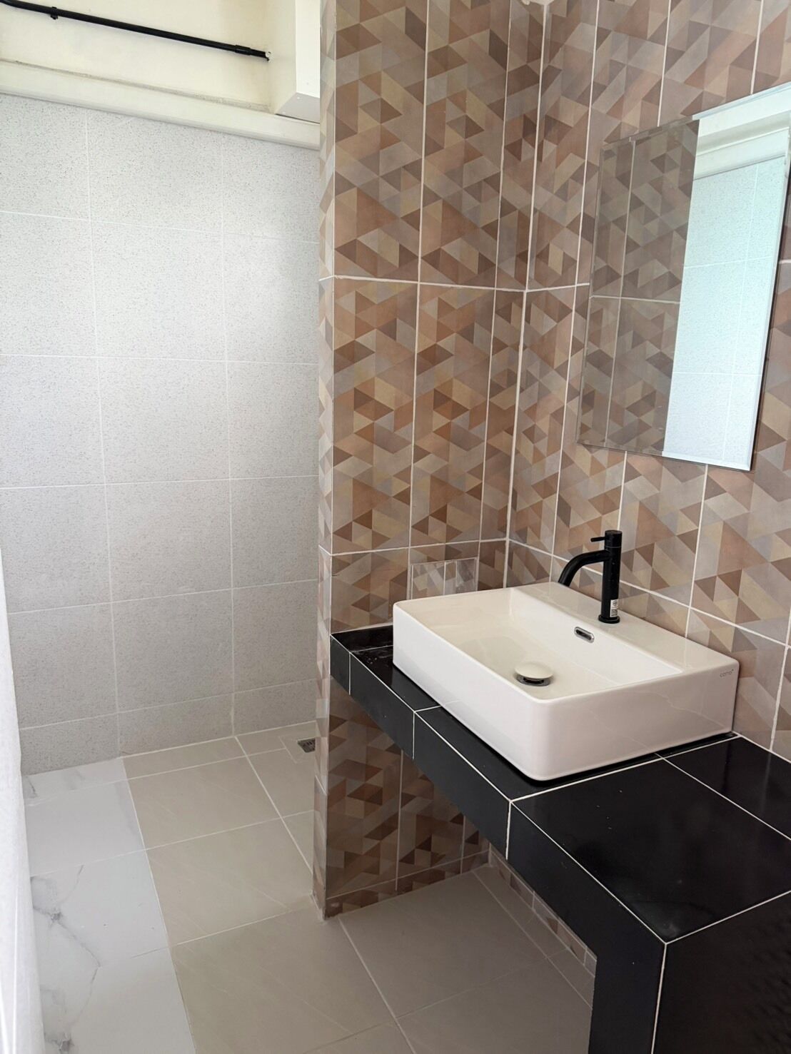 A bathroom with a white sink, black countertop, and geometric patterned tiles.