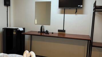 A hotel room with a bed, a desk, a flat-screen TV, a mirror, an air conditioner, and a heater.