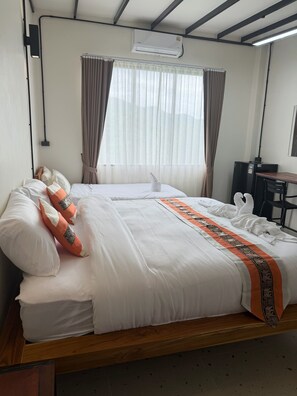 A hotel room with two beds, a desk, and an air conditioning unit. - Mountain Blues Hotel (Pai)