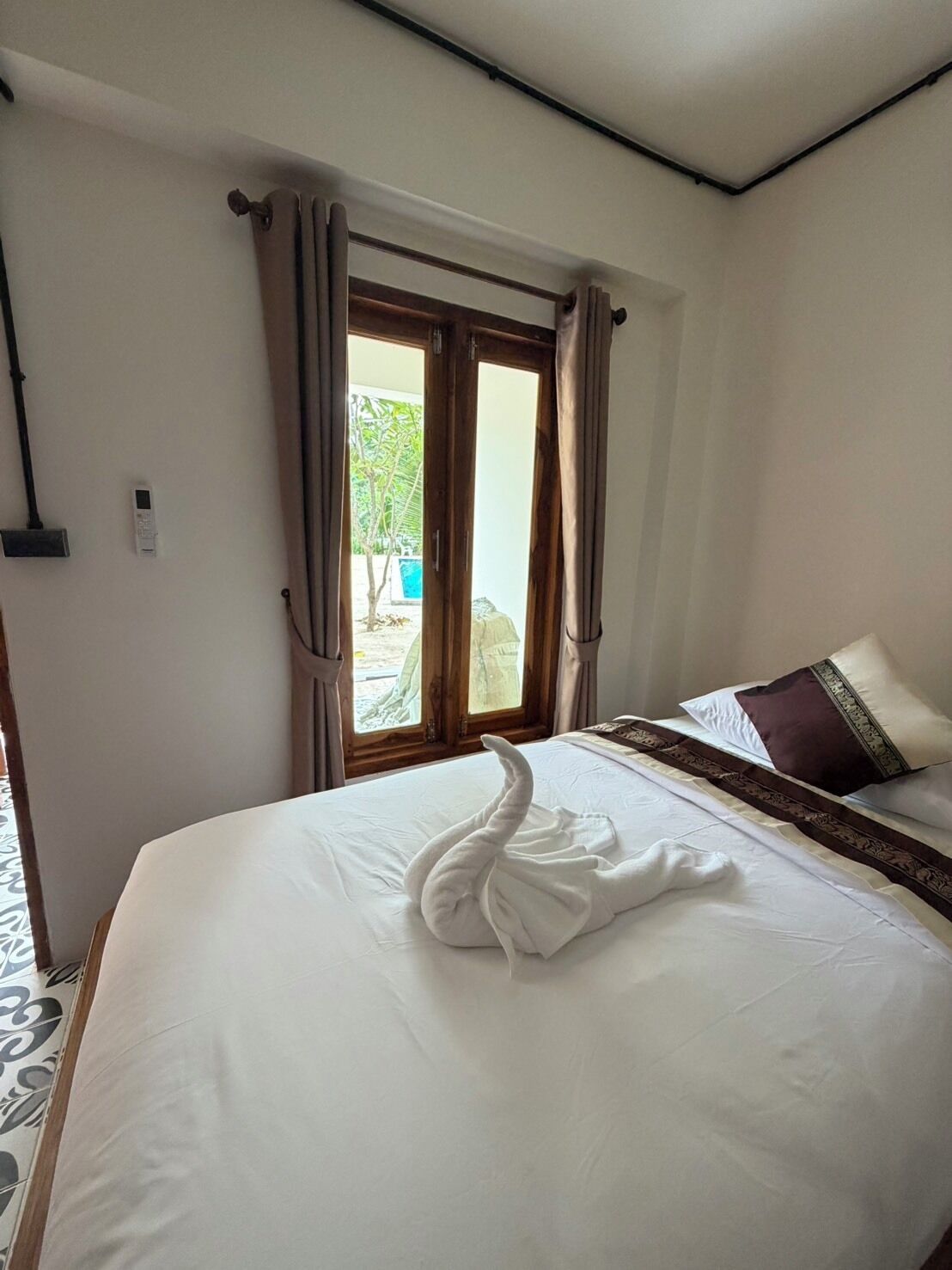 A hotel room with a bed, curtains, a window, and a view of the outdoors.