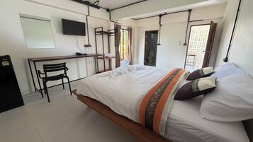 Un dormitorio con cama, escritorio, silla y televisor en la pared.