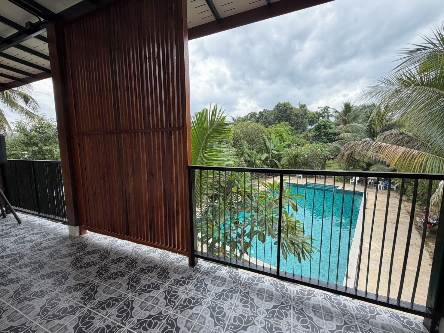 A covered balcony with a pool, surrounded by tropical vegetation.