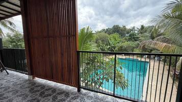 A covered balcony with a pool, surrounded by tropical vegetation.