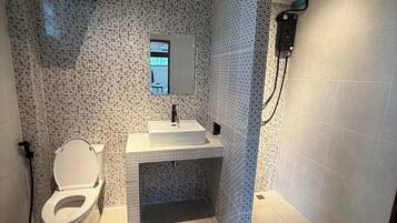 Un baño con inodoro, lavabo y zona de ducha.