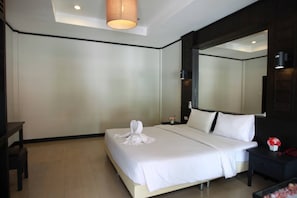 A hotel room with a large bed, a bedside table, a nightstand, a mirror, and a hanging light fixture.