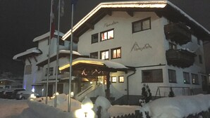 Un hotel con fachada cubierta de nieve y entrada iluminada.
