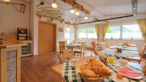 Un comedor con manteles a cuadros, sillas de madera y una cesta de pan.