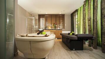 Relax in a spacious bathroom with a large round bathtub and adjacent massage table.