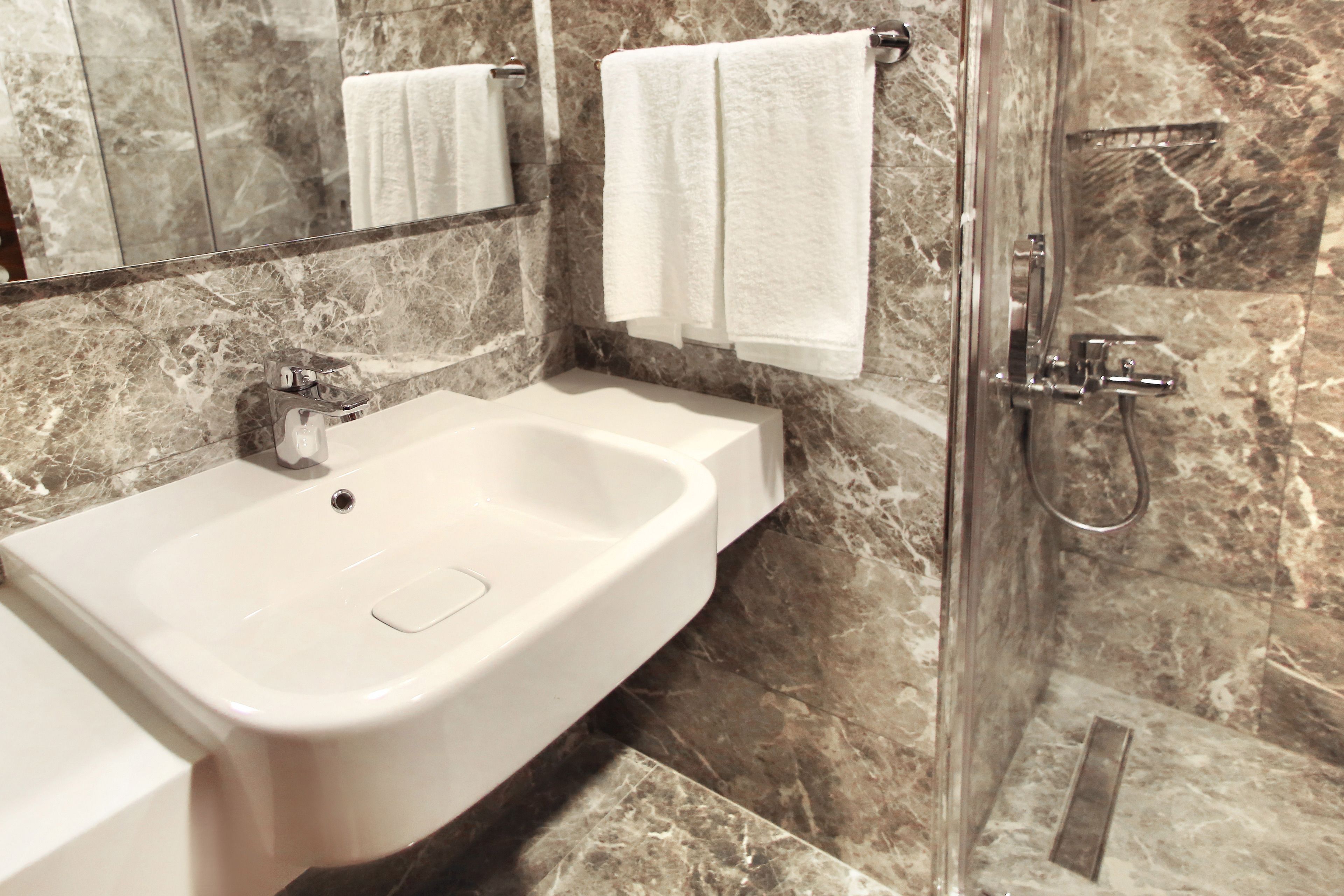 A bathroom with a white sink, a mirror, and a shower area.