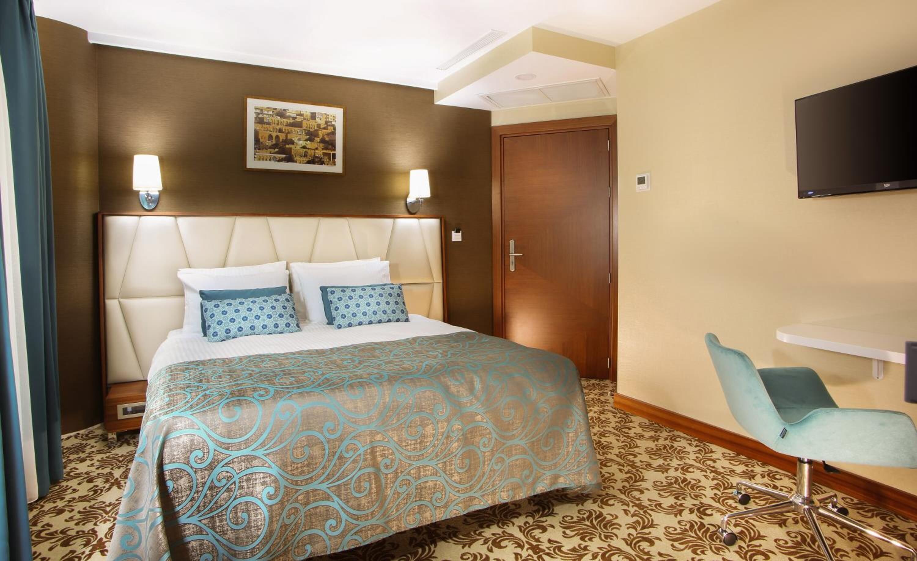 Habitación de hotel con una cama grande, un escritorio, una silla y un televisor.