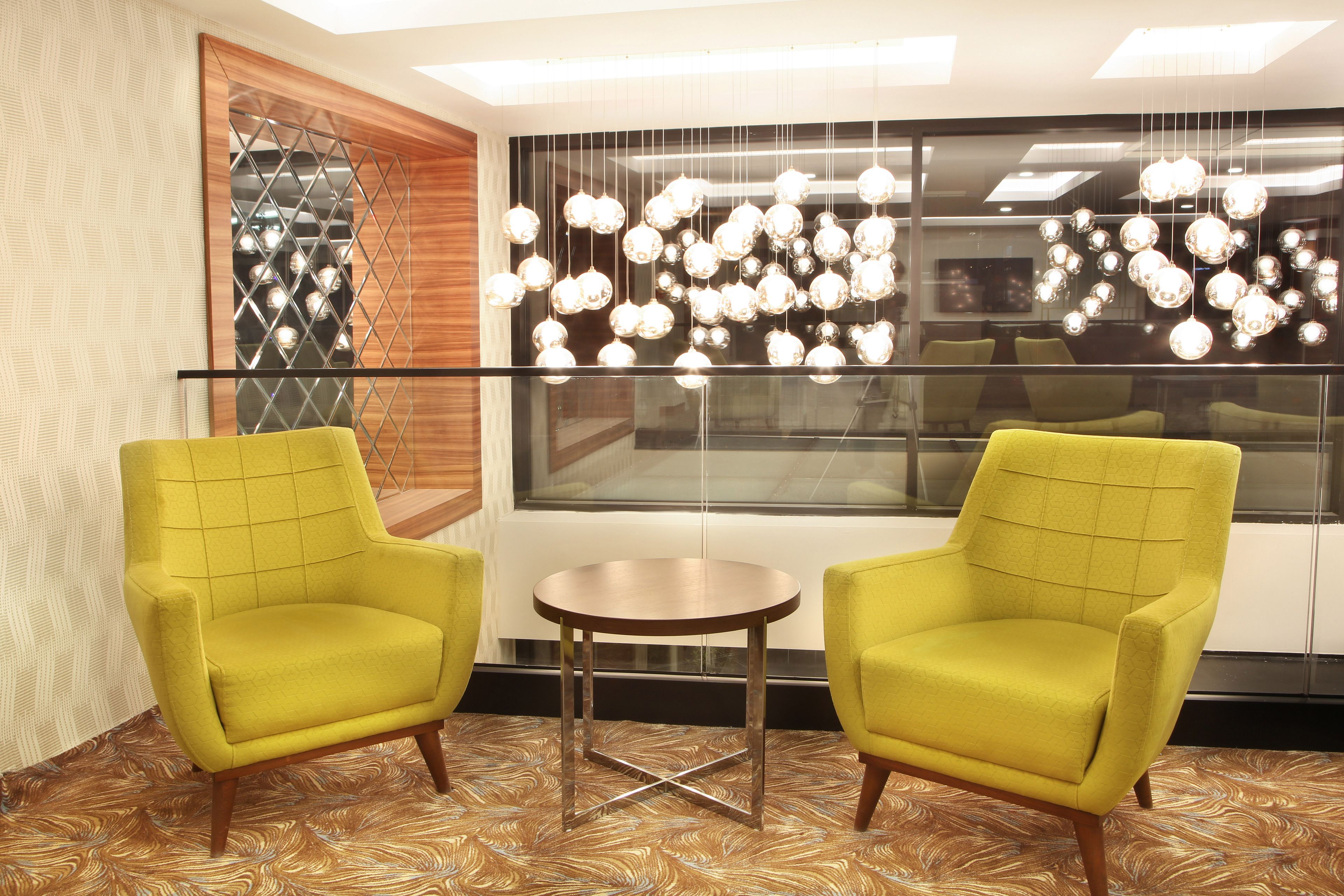A room with two yellow armchairs, a small round table, and a decorative light fixture.