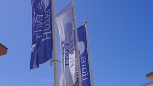 A hotel with multiple flags on a flagpole, surrounded by buildings.