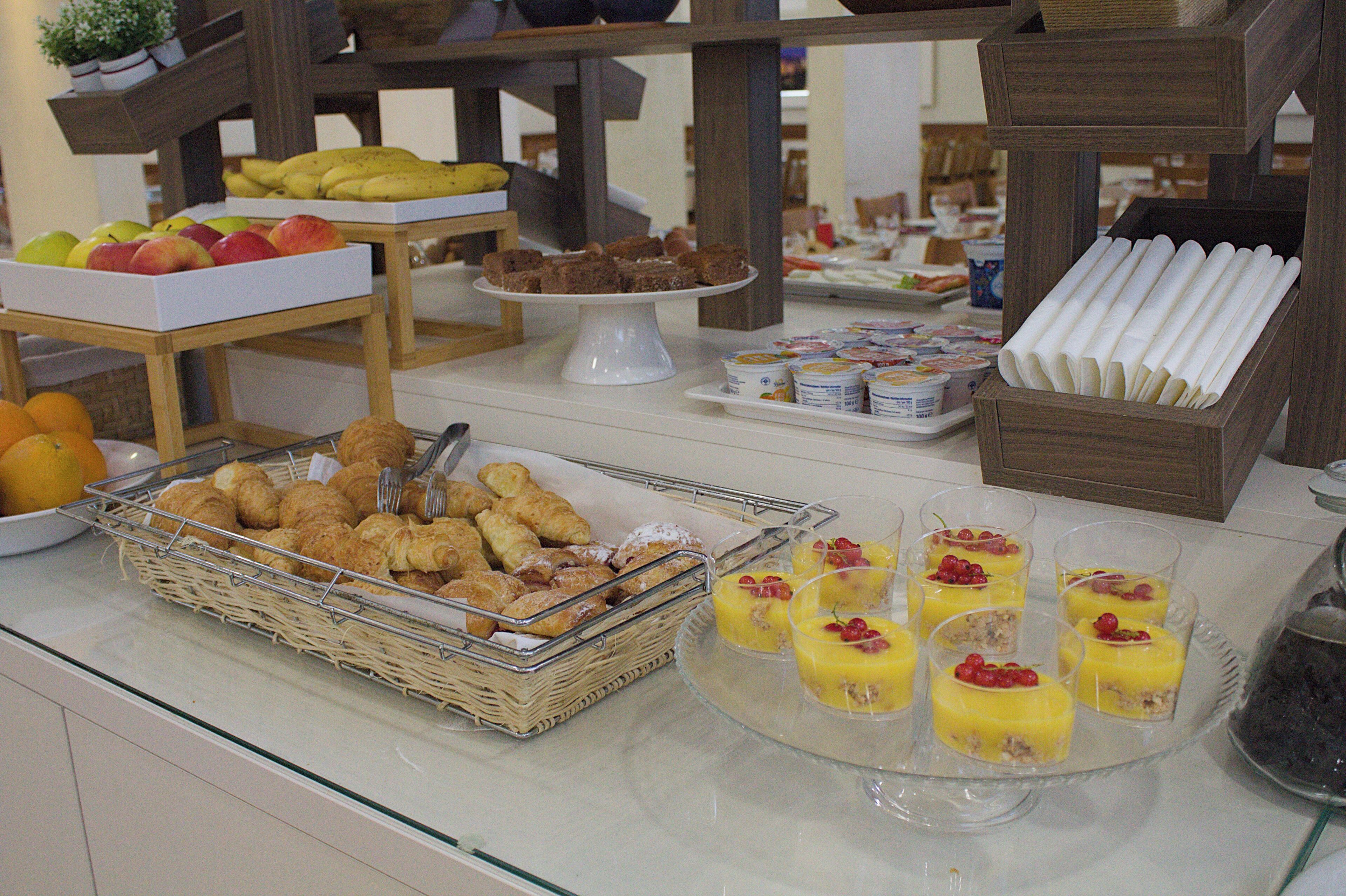 Un bufé con diversas opciones de comida, entre ellas frutas, pasteles y postres.