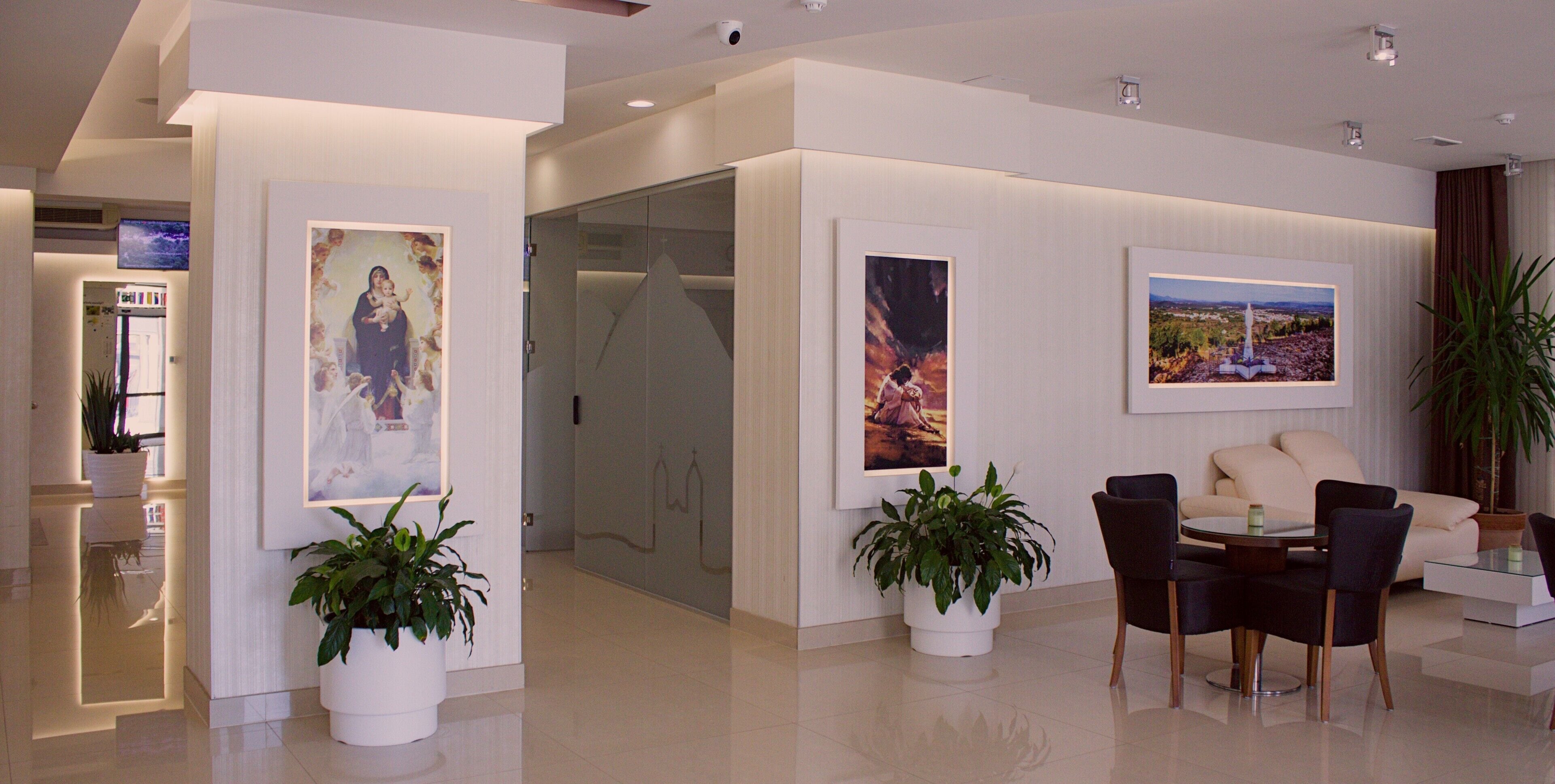 A modern interior with a seating area, potted plants, and framed artwork on the walls.