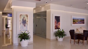 A modern interior with a seating area, potted plants, and framed artwork on the walls.
