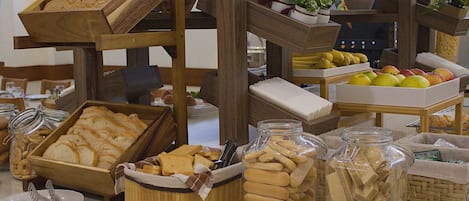 Un bufé con diversas opciones de comida, incluyendo pan, galletas y frutas.