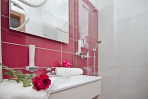 A bathroom with a white sink, a mirror, and a red-tiled wall. - Hotel Luna (Citluk)