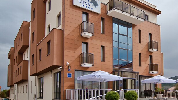A hotel with a modern design, featuring a prominent sign, balconies, and outdoor seating.