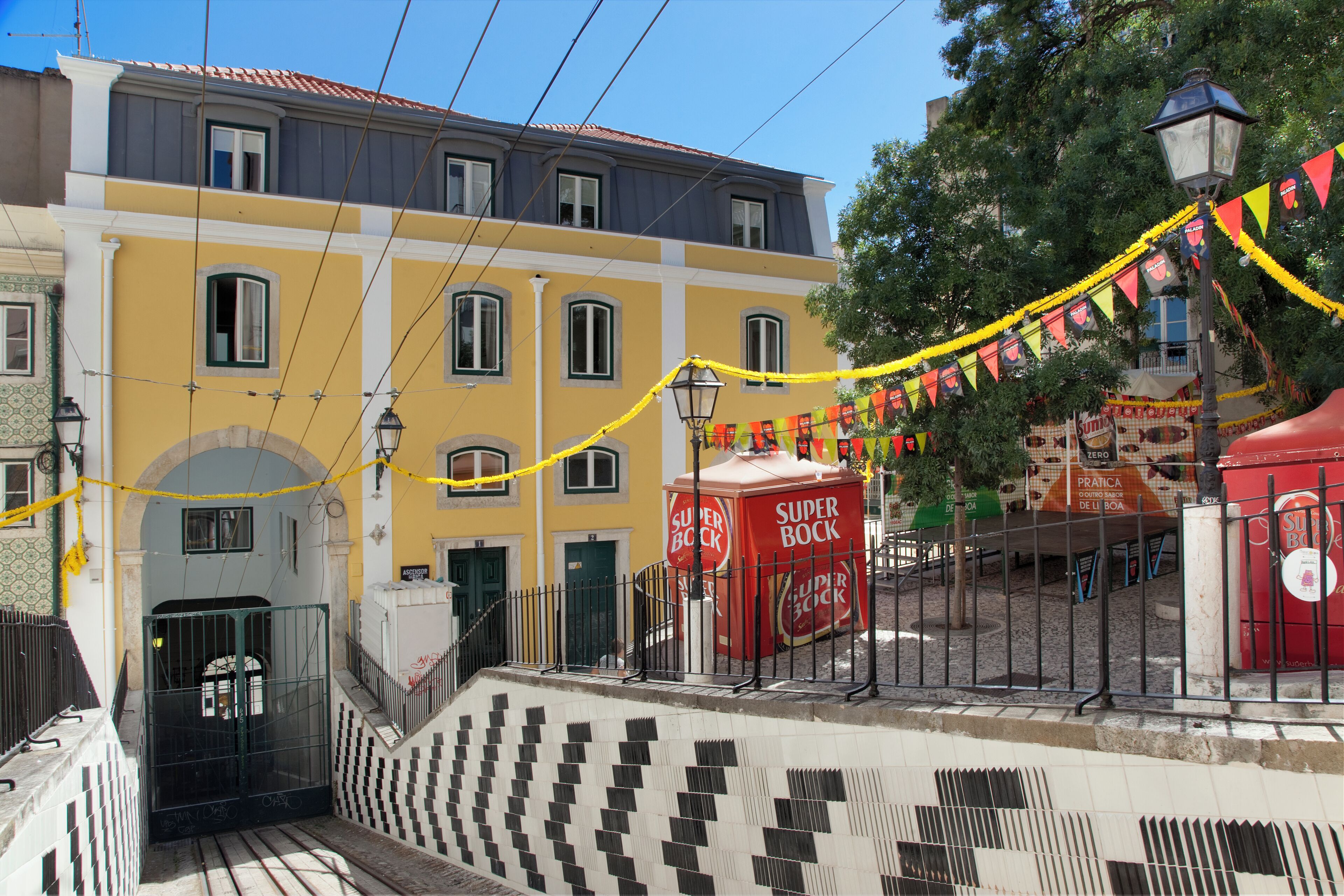 Un edificio amarillo con varias ventanas, un portón negro y un anuncio rojo de Super Bock.