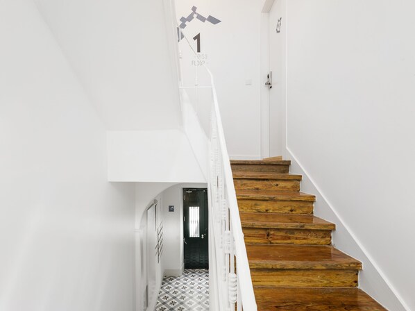 A staircase with wooden steps and white walls, leading to a door marked '1'. - LSA Castelo S. Jorge by Numa (Lisbon)