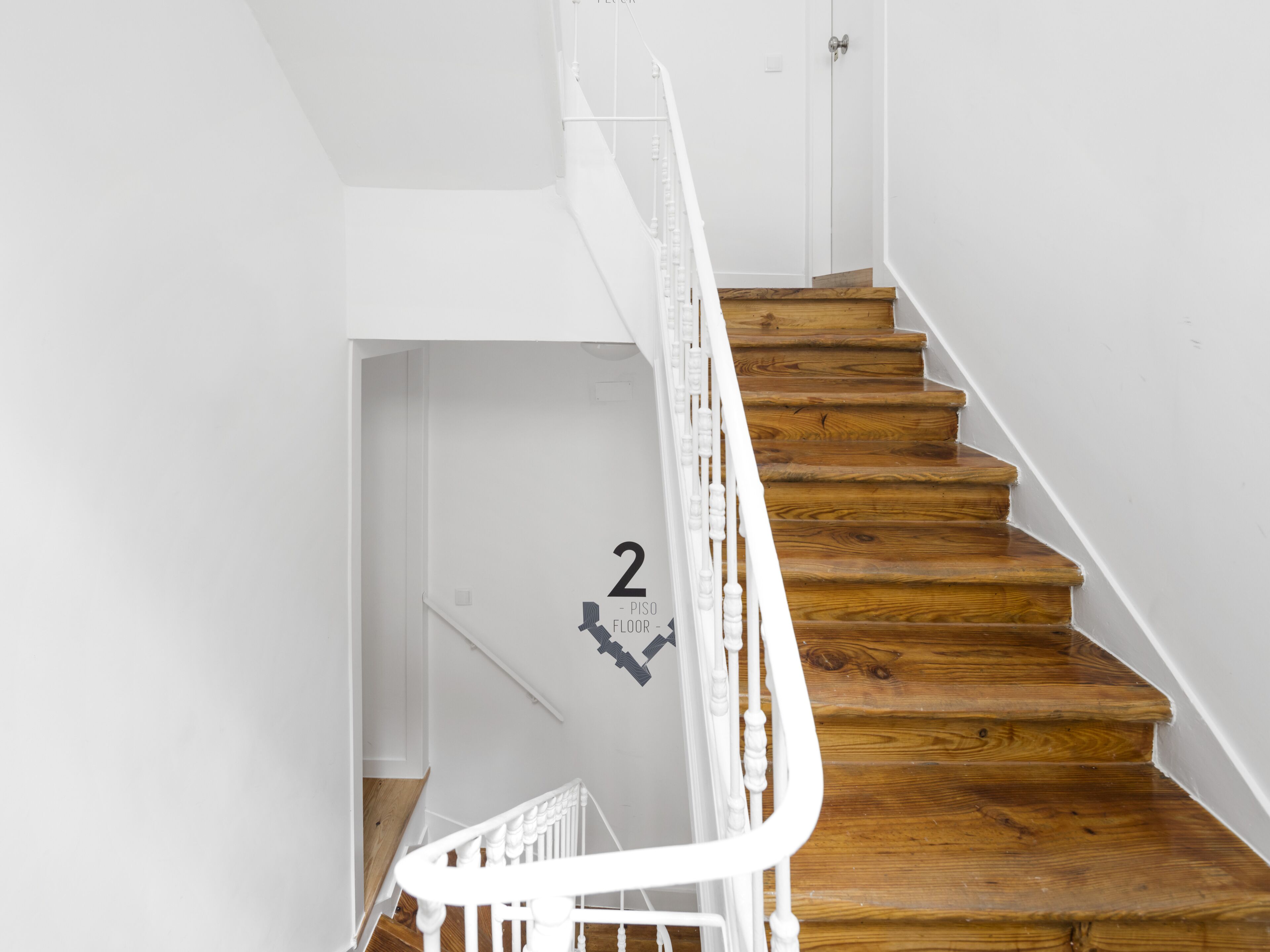 A staircase with wooden steps and white railings, leading to an interior space.