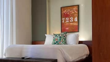 A bedroom with a bed, a wooden bench, a painting, and a tiled floor.