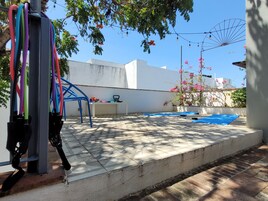 Un patio con un tapete azul, una pared blanca y una silla de metal.