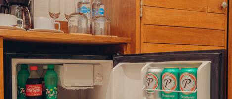A compact refrigerator stocked with beverages and a coffee maker.