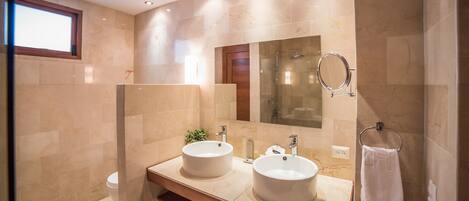 A modern bathroom with two sinks, a large mirror, and a towel rack.