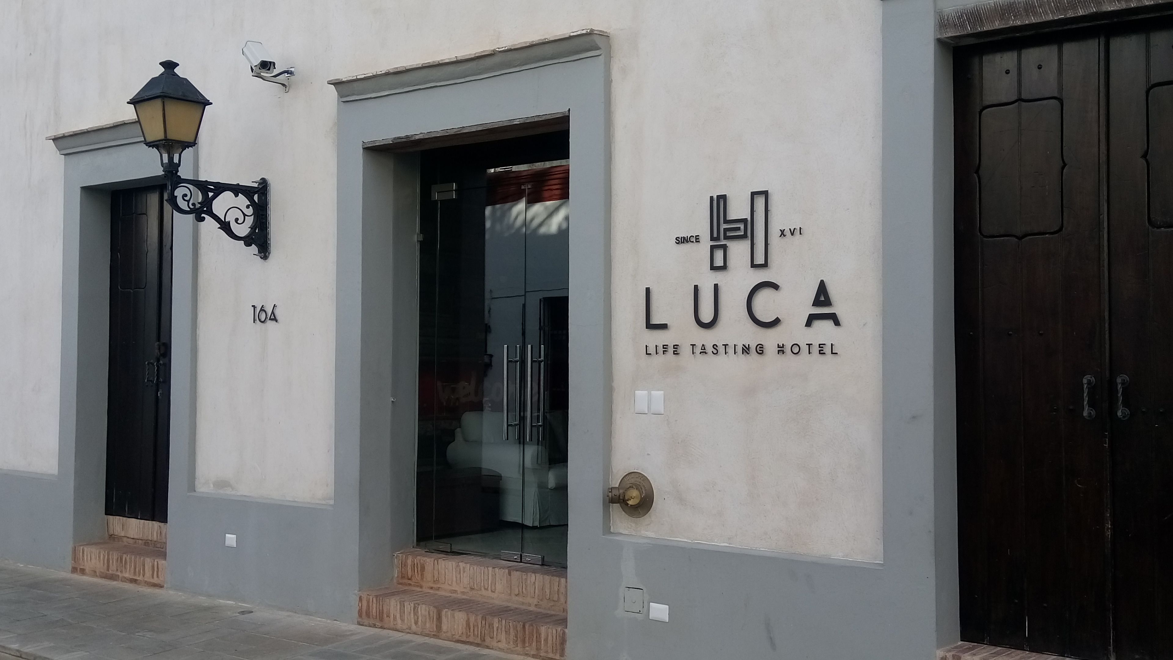 A building with a sign reading "Luca Life Tasting Hotel" and a door with a glass entrance.