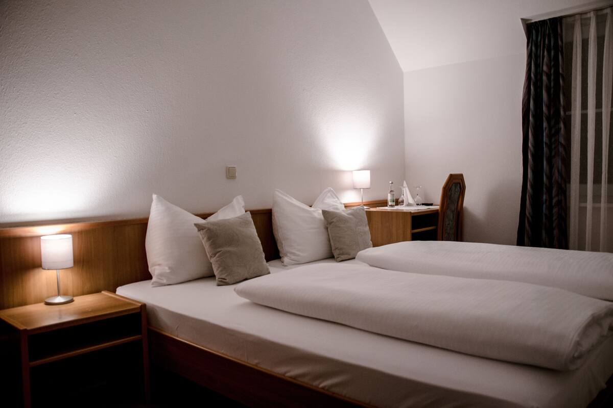 Habitación de hotel con una cama grande, dos mesitas de noche, una lámpara y un espejo.