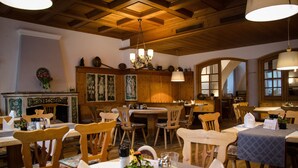 A restaurant with wooden furniture, a chandelier, and a fireplace. - Hotel Blaue Traube (Schongau)