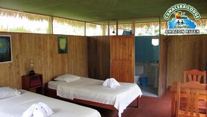 A room with two beds, wooden walls, a wooden chair, and a small table. - Cumaceba Amazon Lodge (Belén)