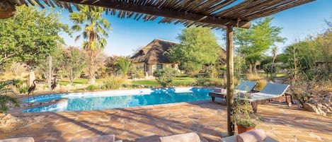 Una piscina al aire libre, sillones reclinables de piscina