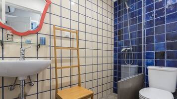 A bathroom with a sink, mirror, wooden chair, and a toilet.