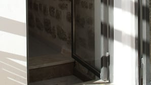 Un umbral que da a un cuarto con pared de piedra y marco de puerta metálico.