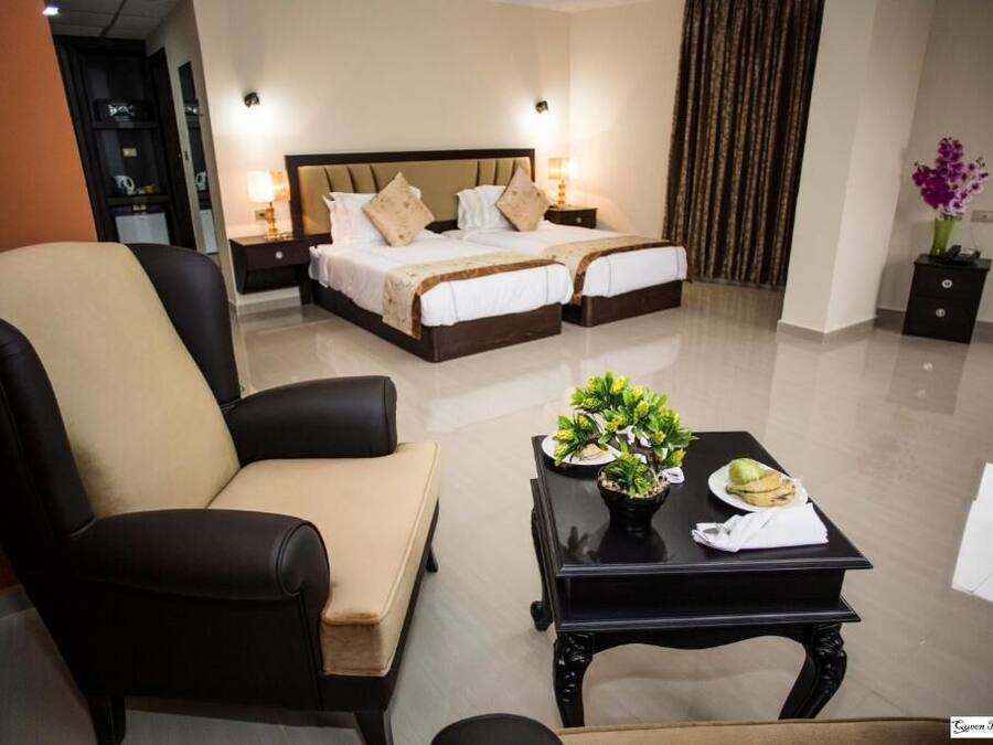 A hotel room with a bed, a sofa, a small table with a plant, and a nightstand.