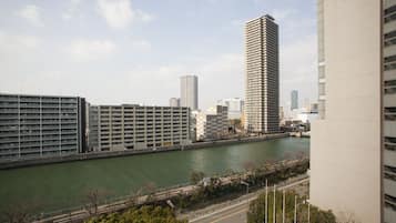 A high-rise building with a river in the foreground and other buildings in the background.