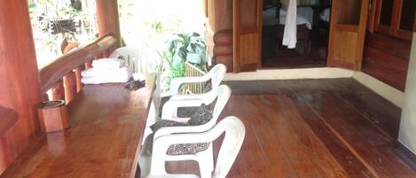 A wooden deck with a dining table and chairs, a wooden door, and a view of a garden.