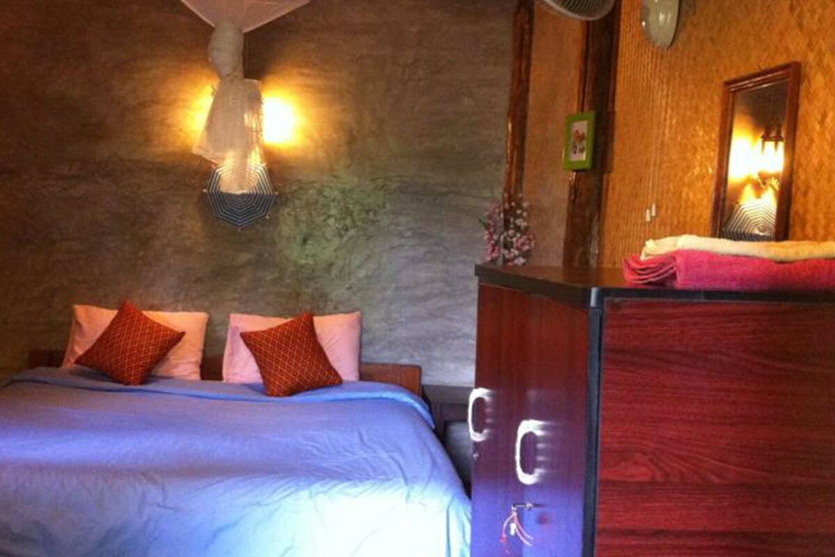A bedroom with a bed, a dresser, and a wall-mounted light fixture.