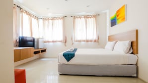 A modern hotel room with a bed, a TV, and a desk. - Portrait Pranburi Hotel (Pranburi)