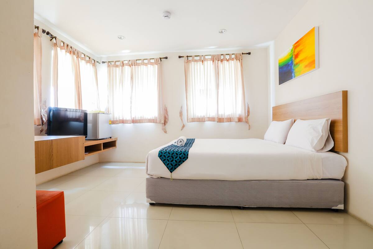 Una habitación de hotel moderna con cama, televisor y escritorio.