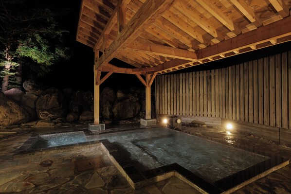 A stone-floored hot tub area with wooden beams and a wooden wall.