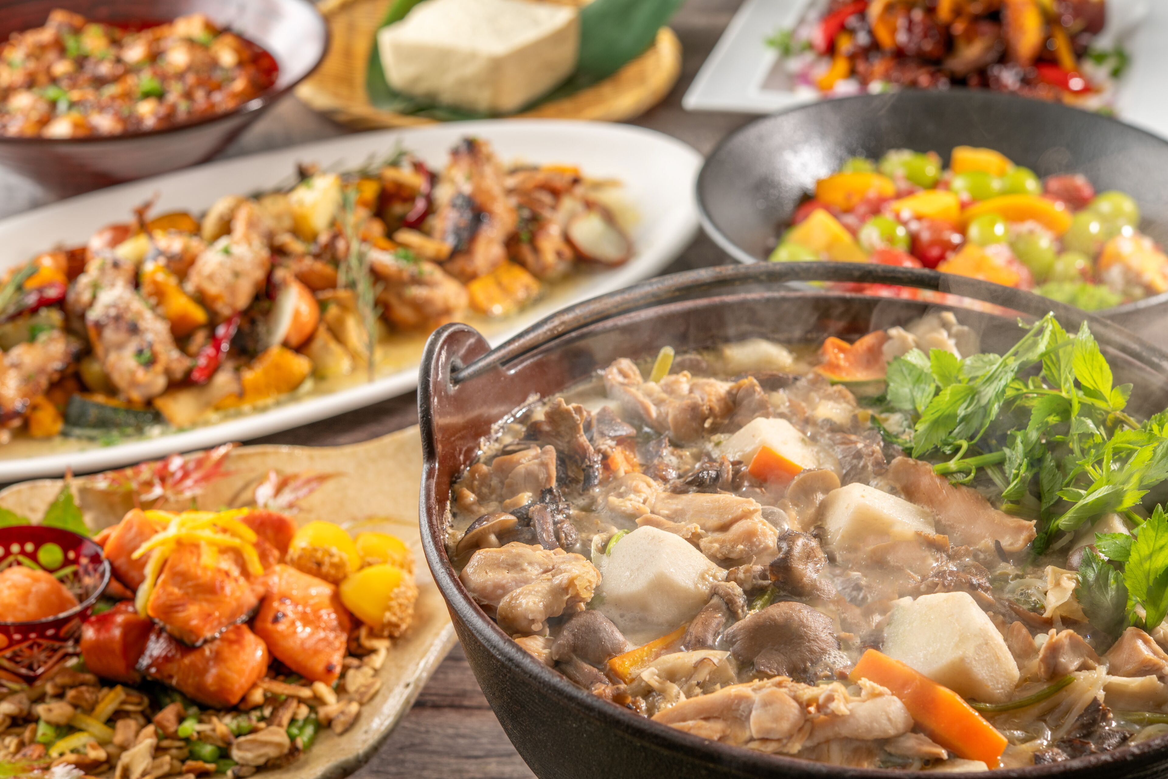 A variety of dishes, including a hot pot with meat and vegetables, a plate with skewered meat, and a bowl of mixed vegetables.