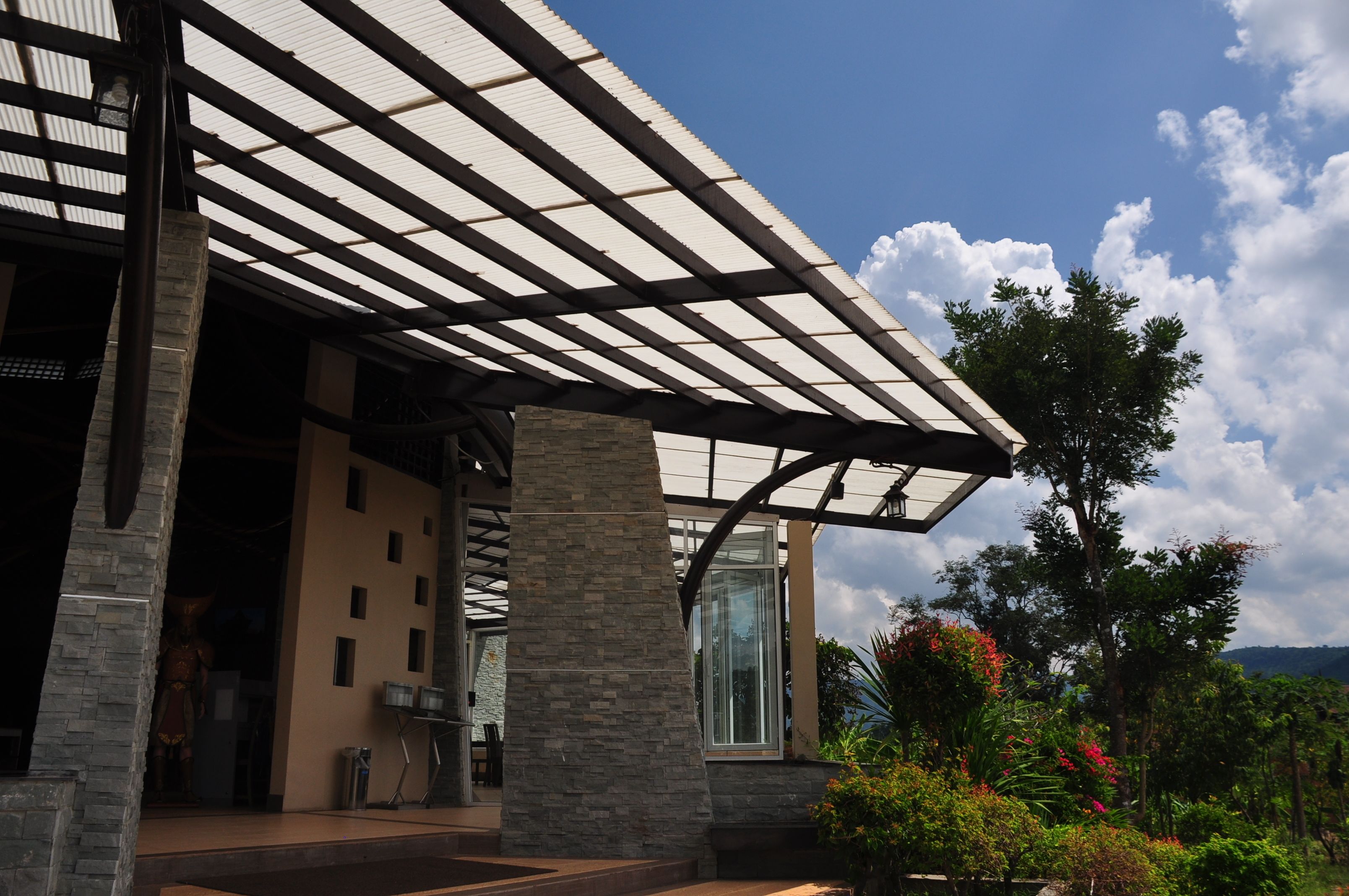 A modern building with a glass facade, stone pillars, and a covered entrance area.