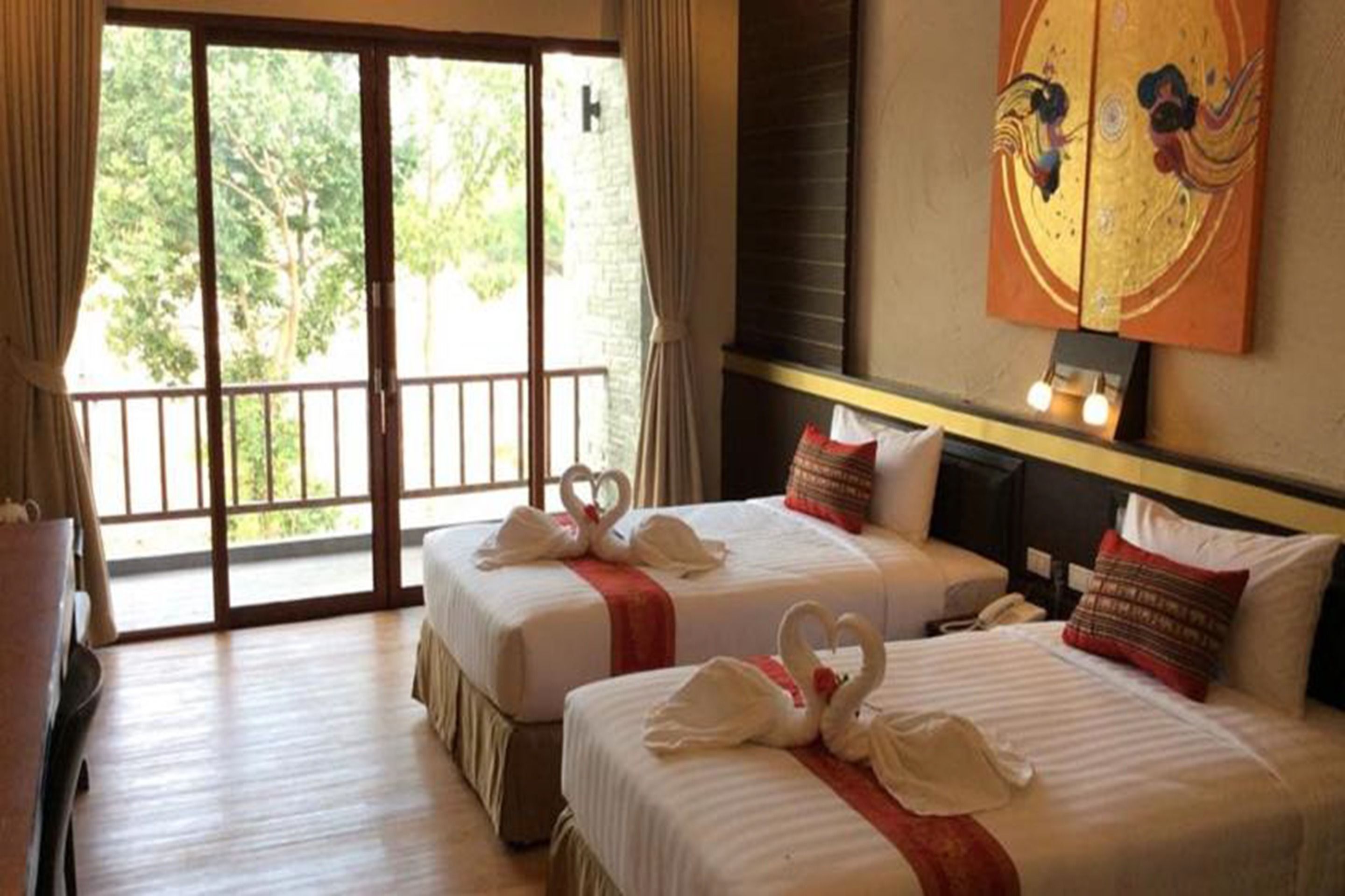 A hotel room with two beds, a balcony, a painting on the wall, and a desk.